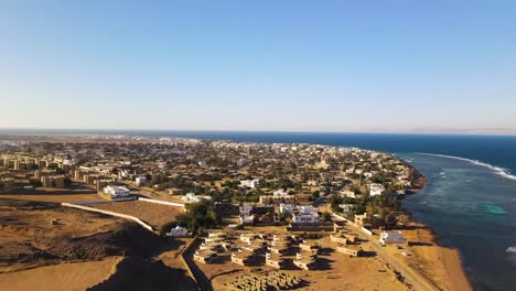 An-aerial-perspective-showcases-the-charming-residential-area-nestled-by-the-sea-in-Dahab,-Egypt,-evoking-a-sense-of-coastal-tranquility-and-seaside-living