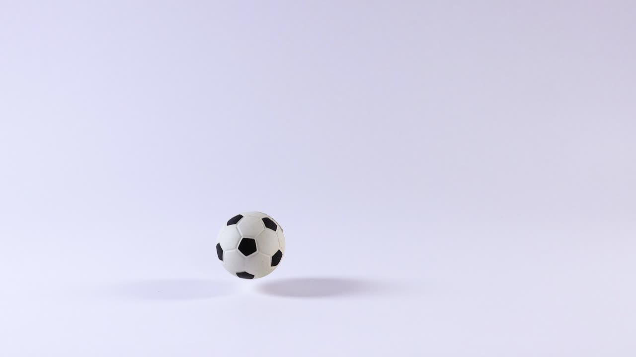 A soccer ball bounces on a white surface