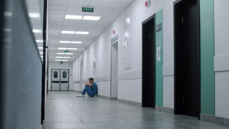 medicine worker sitting floor ambulance hallway. medic resting after surgery.