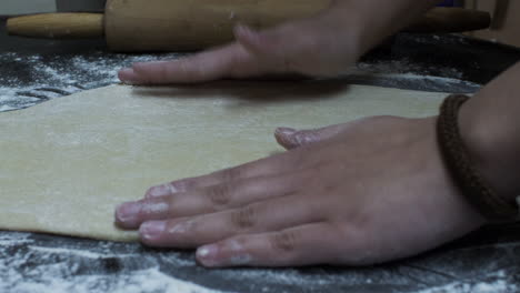 female hands kneading and flattening dough on table