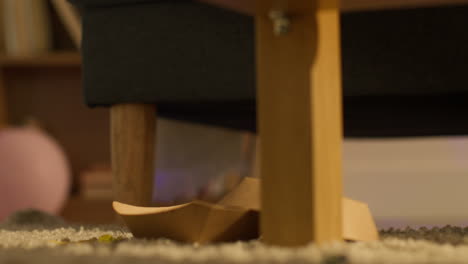 Close-Up-Of-Man-On-Sofa-Picking-Up-Beer-Bottle-And-Snack-From-Floor-At-House-Party