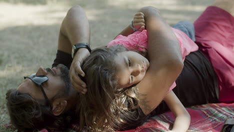 tired daughter lying with dad on blanket during picnic