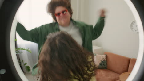 young bloggers dancing energetically in front of ring light setup at home