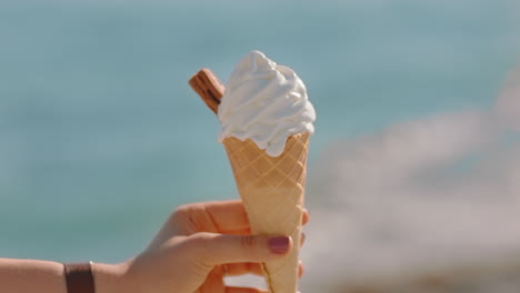 mujer de mano cercana sosteniendo helado de vainilla con sabor a postre en una hermosa playa soleada disfrutando de las vacaciones de verano comiendo soft serve