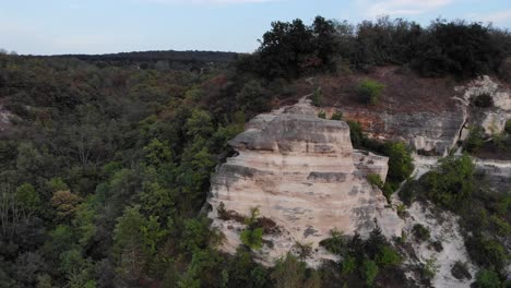 dron aéreo lento y épico orbita alrededor de una roca sólida interesante en la hora del atardecer con un hermoso entorno forestal