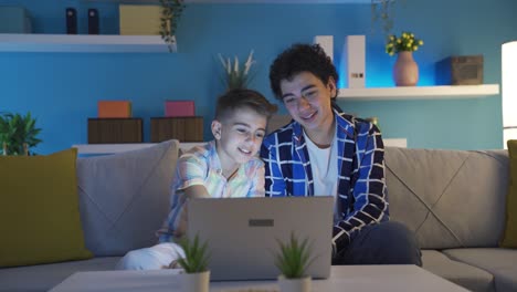 Two-brothers-watching-funny-movie-on-laptop-and-laughing.