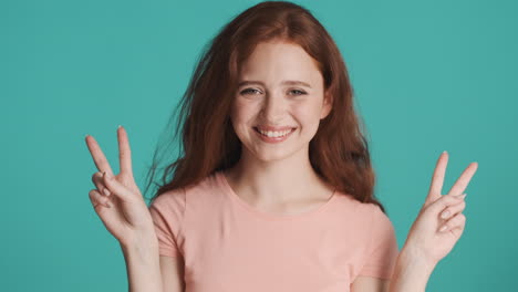 Redheaded-girl-looking-at-camera-on-turquoise-background.