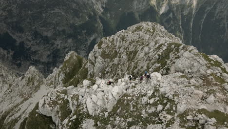 Toma-De-Drones-De-La-Perspectiva-De-Los-Ojos-De-Los-Pájaros-Rombon-De-La-Montaña,-Mirando-Al-Grupo-De-Excursionistas-Escalando-En-La-Cima