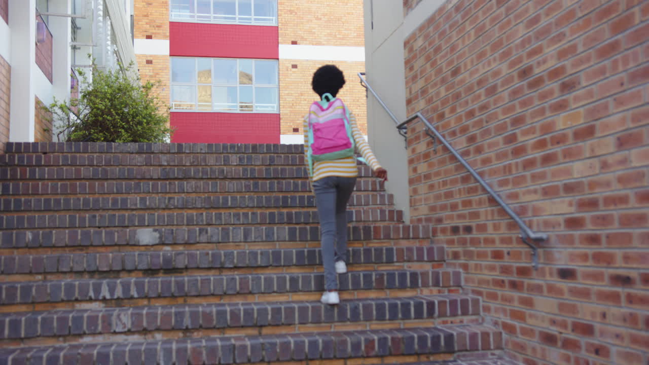 Walking up stairs, student with backpack heading to school building, copy space