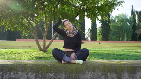 yoga-teacher-stretching-neck-in-park,-nice-flash-of-sunlight