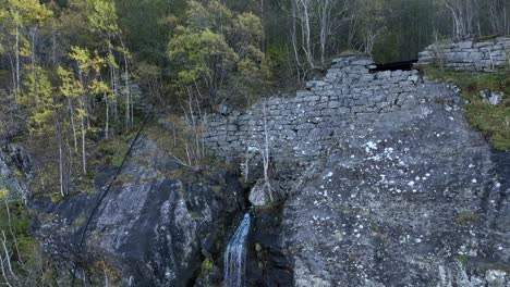 perfecto muro de piedra hecho a mano a lo largo del ferrocarril desmantelado de bergen noruega, se acerca a la pared y pequeña cascada