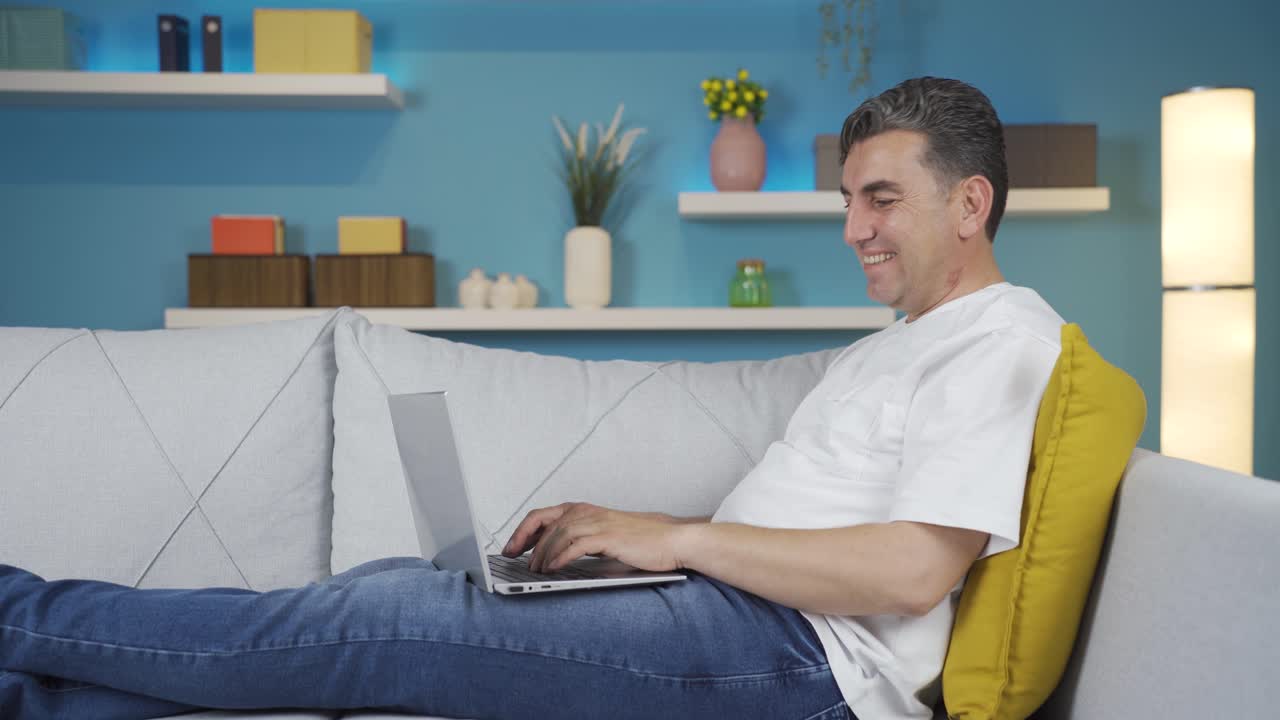 hombre usando computadora portátil con expresión feliz en casa.