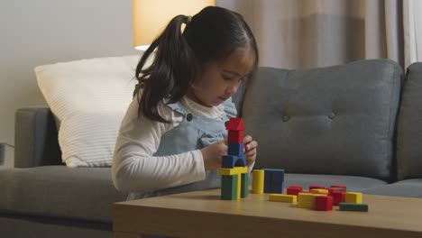 Young-Girl-At-Home-Playing-With-Colourful-Wooden-Building-Blocks