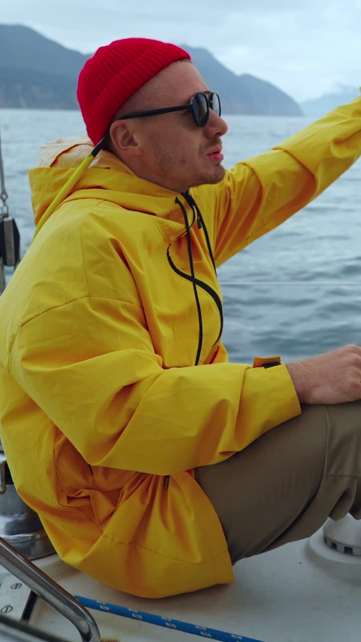 Ung mand i gul jakke og rød hue sejler på havet