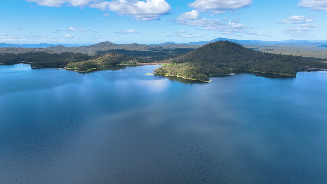 Flight high above the mystical waters of Lake Teemburra towards a headland, and then curves right towards the dam wall and across the lush forests of the Mackay plain, Central Queensland Australia