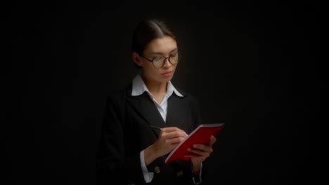 una mujer de negocios escribe con confianza en un cuaderno rojo y pone su firma.