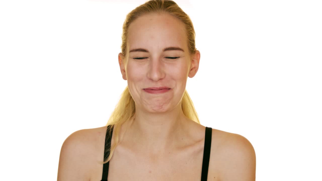 Cheerful happy young beautiful girl looking at camera smiling laughing over white background. Slow motion studio shoot.