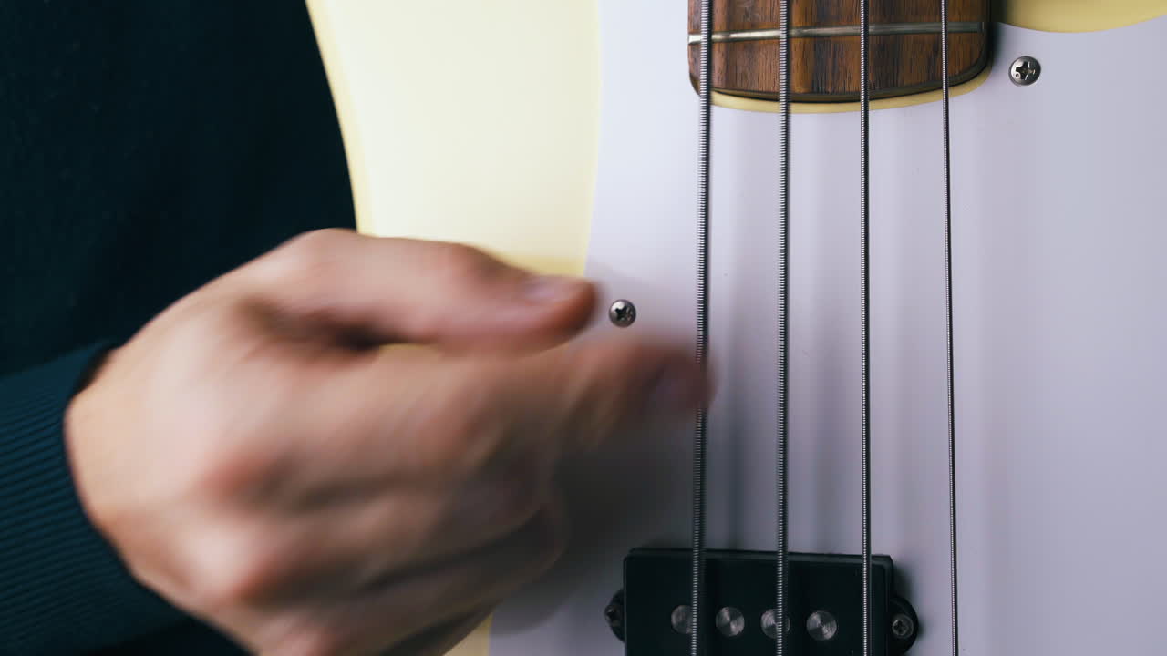 funky artist plays on metal string of white bass guitar