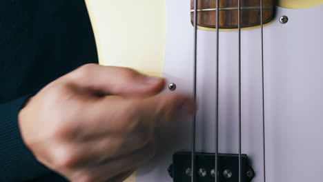 artista funky toca en la cuerda de metal de la guitarra baja blanca