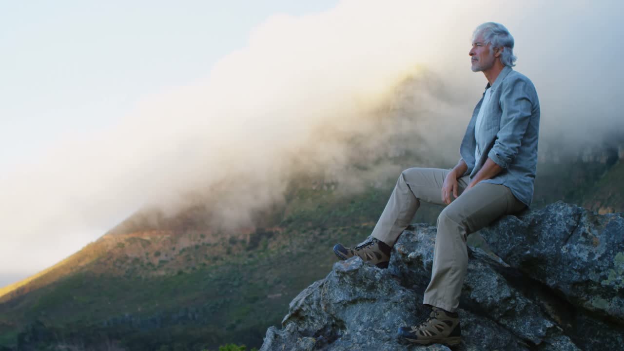 Senior man relaxing on a rock at countryside 4k