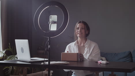 excited young vlogger woman showing to the camera the package she has received and preparing to open it