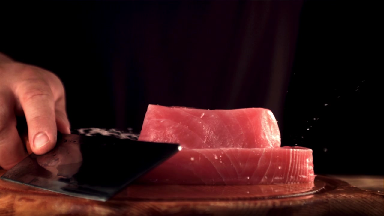 Tonno fresco crudo che cade in super rallentatore con schizzi d'acqua