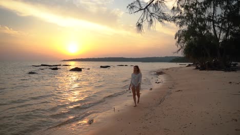 Schöne-Junge-Frau-Mit-Blonden-Haaren-Geht-Während-Des-Sonnenaufgangs-Am-Schönen-Strand-Von-Koh-Rong-Spazieren,-Während-Kleine-Wellen-Am-Strand-Ausrollen