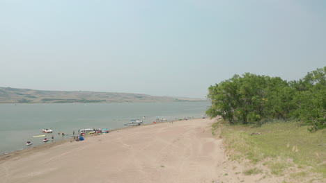 wide aerial pan of people and boats on beach at saskatchewan landing, canada