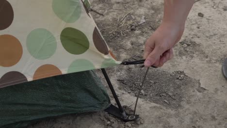 outdoor nature woman taking pegs out of ground packing up tent