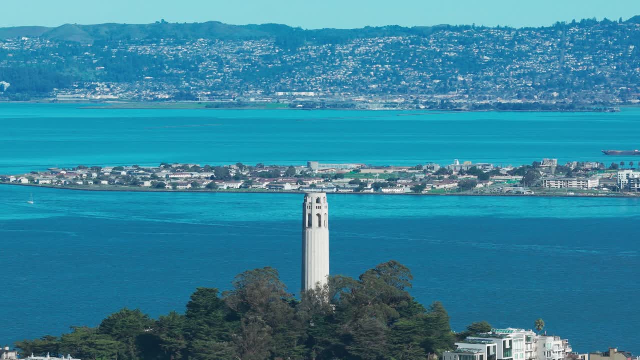 Ripresa panoramica aerea da teleobiettivo della Coit Tower con Treasure Island in lontananza in una giornata luminosa e soleggiata a San Francisco. 4K