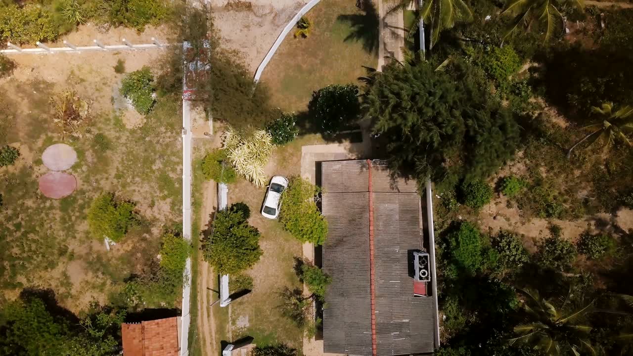 drone ascendiendo y alejándose en idílica casa de vacaciones tropicales en la encantadora costa del océano con palmeras y olas tranquilas