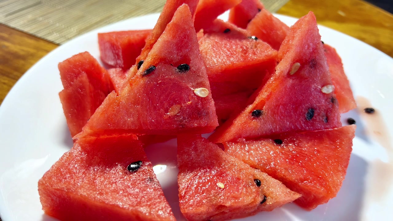 Gros plan d'une main prenant un morceau triangulaire de pastèque rouge fraîche dans une assiette. Idéal pour l'alimentation saine, les repas d'été, le marché aux fruits et les campagnes de nutrition.