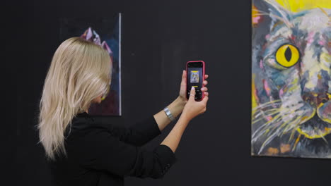 mujer tomando una foto de arte en la galería