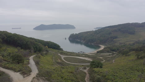 View-of-a-bay-surrounded-with-green-forest,-and-an-island-in-far-distance,-on-a-cloudy-overcast-day