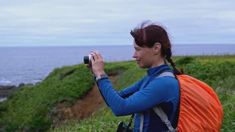 woman hiking and taking pictures of ocean coastline