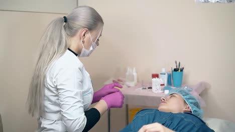 el maestro de las cejas sostiene un tubo con pintura en la mujer en el sofá
