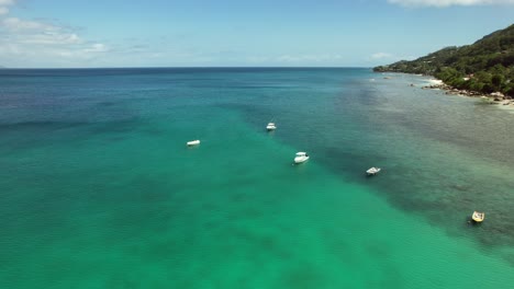 Toma-De-Drones-De-Barcos-Que-Atracan-Cerca-De-La-Playa-De-Beau-Vallon,-Mar-Tranquilo-Y-Día-Soleado,-Agua-Clara