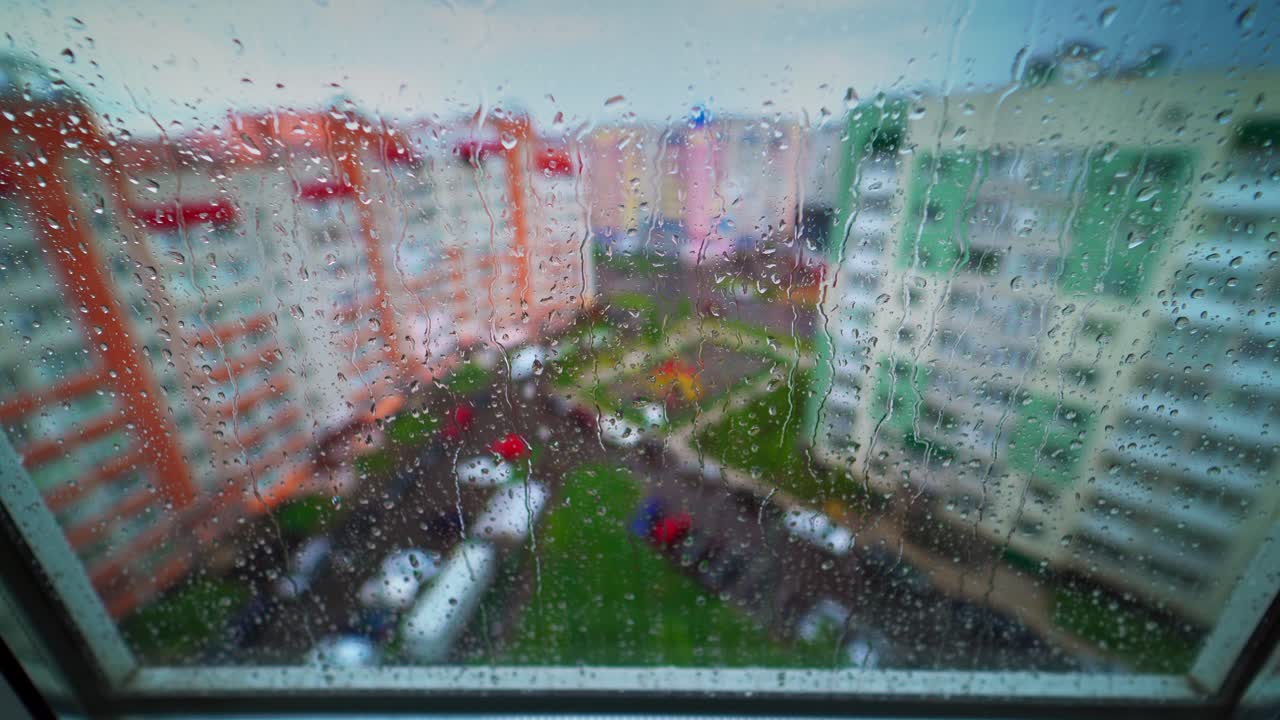 Rain drop on window at rainy day. Raindrops on window flowing down on glass on the city background. Rainy weather in town.