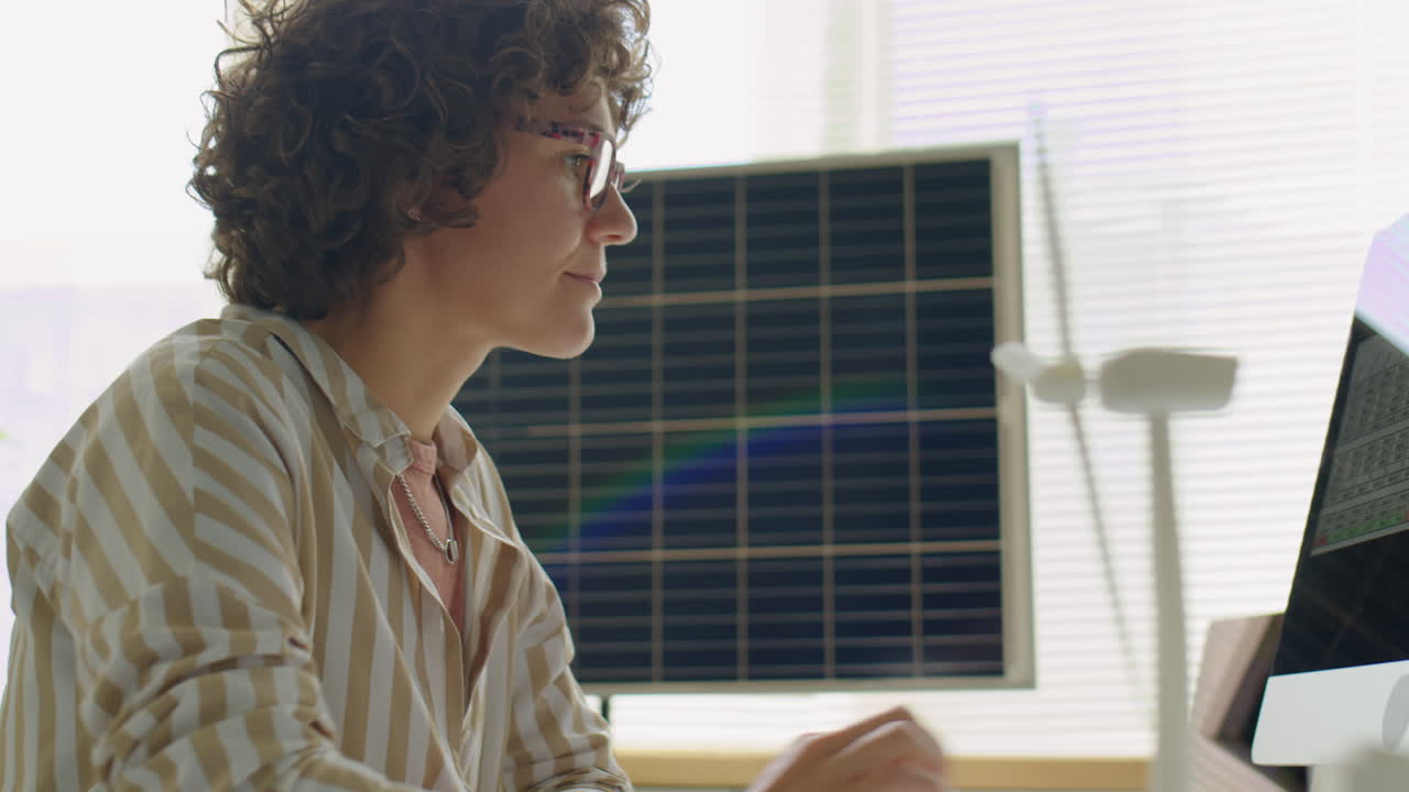 Female Renewable Energy Engineer Working on Computer in Office