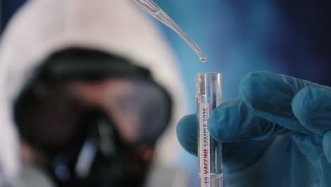 biólogo protegido por un mono y gafas llena un tubo de ensayo con antídoto covid-19