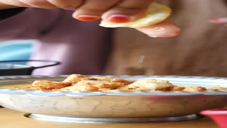 mujer exprimiendo limón sobre sopa con croutons