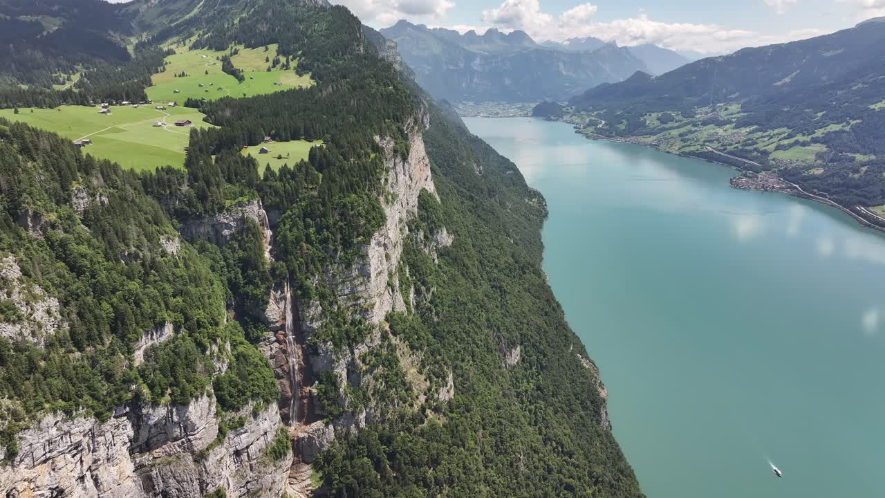 Aerial view of dramatic cliffs above Walensee in Switzerland, showcasing lush alpine meadows and turquoise lake waters in summer
