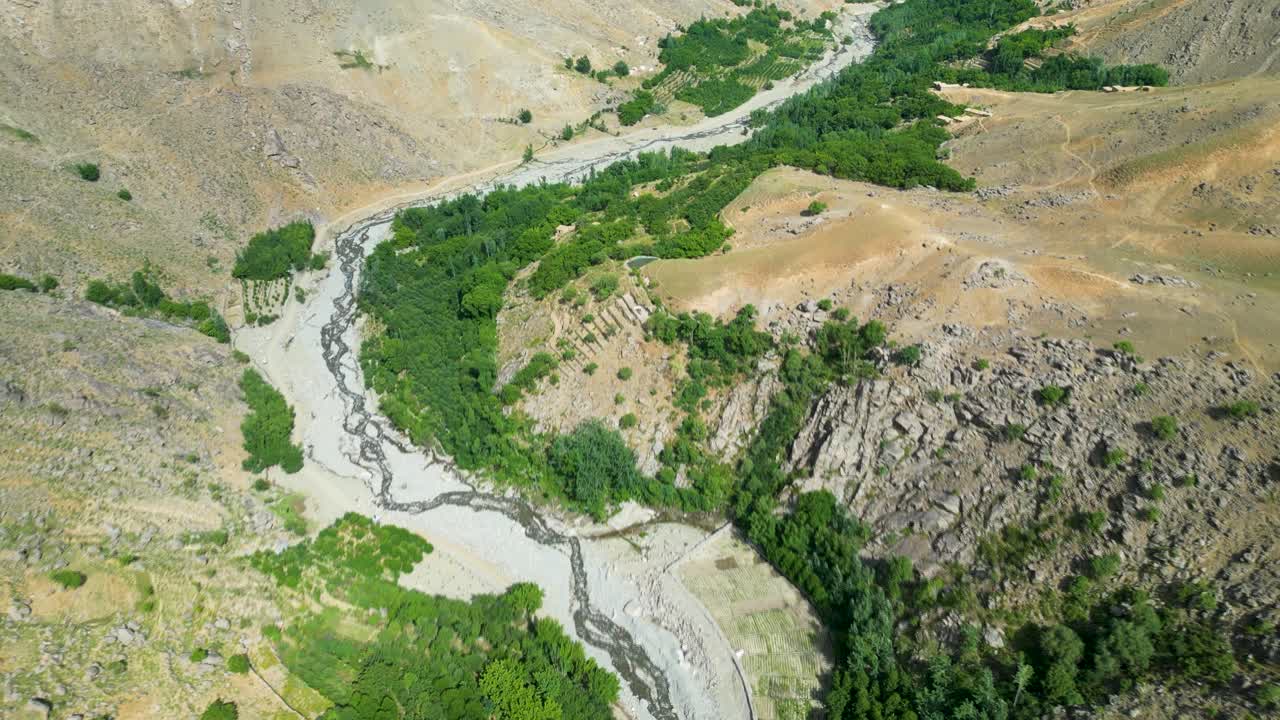 Aerial drone perspective of a river winding through a rugged mountain valley in Kabul, Afghanistan