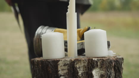 Female-hand-puts-knight-gauntlet-on-stump-with-candles