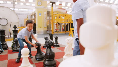 niños de la escuela jugando al ajedrez gigante en un centro de actividades científicas