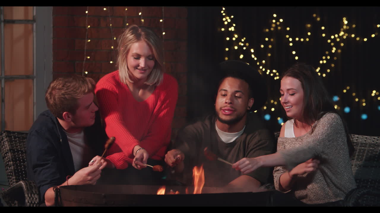 친구 들 의 그룹 이 벽난로  에서 소시지 를 요리 하고 있다