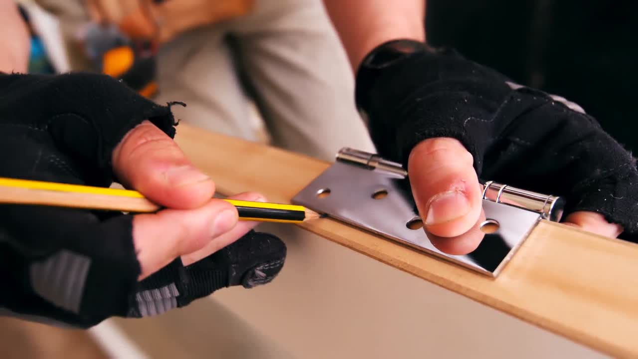 Carpenters hands marking on door with pencil