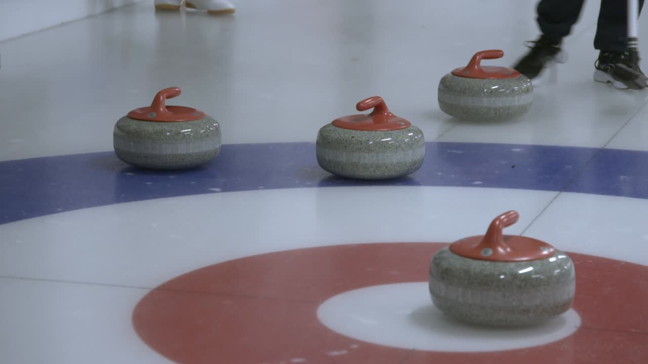 Curling stone hitting two other stones, bouncing the opposite team's stone out of the house