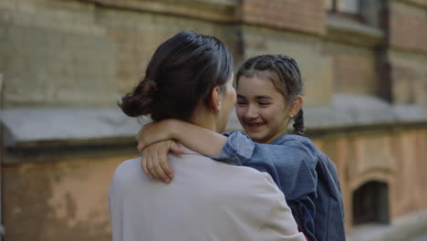 mother and daughter hugging outside school