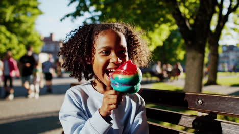 happy girl eating colorful sweet treat in a park